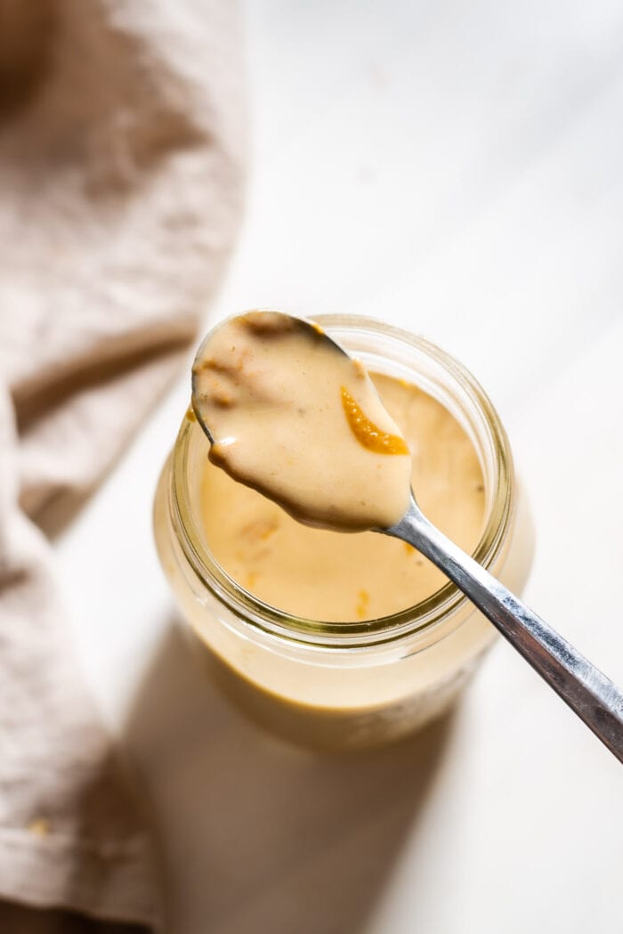 Spoonful of peanut butter smoothie resting on top of jar of smoothie.