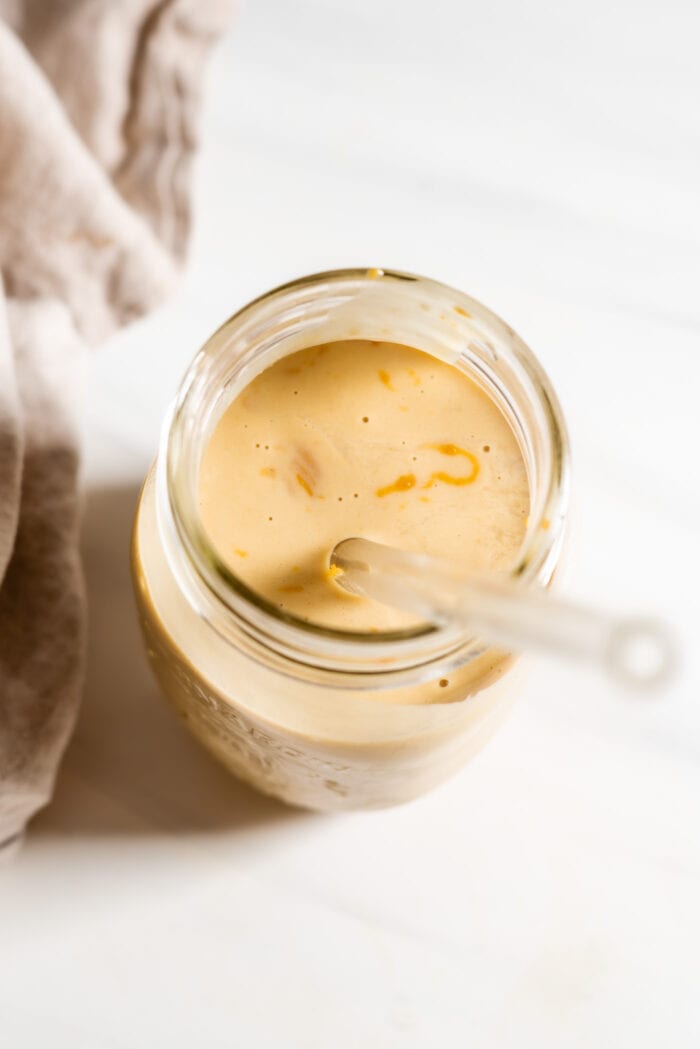 Creamy peanut butter smoothie in a jar with a straw.