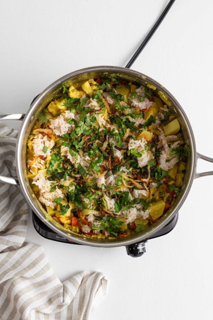 Vegetables, rice and fresh herbs in a large pot.