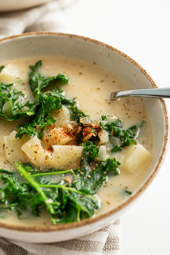 Close up of a bowl of zuppa toscana soup with potato and kale.