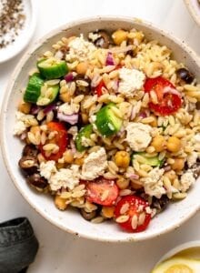 Overhead view of bowl of Mediterranean orzo salad with tomato, cucumber and olives.