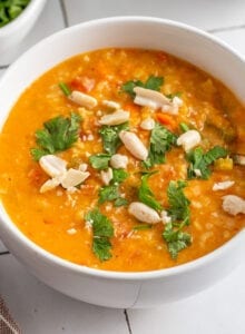 Bowl of mulligatawny soup topped with fresh herbs and peanuts.