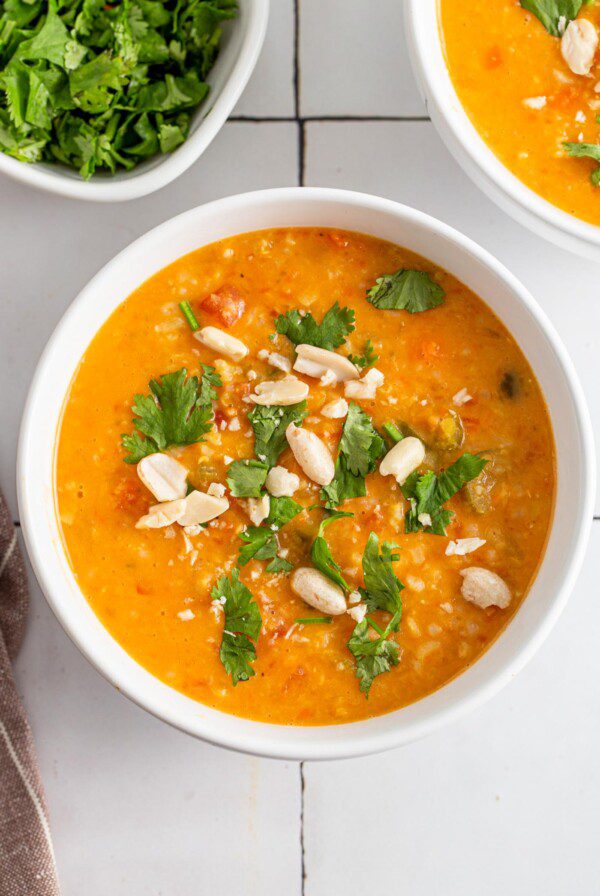 Bowl of mulligatawny soup topped with fresh herbs and peanuts.