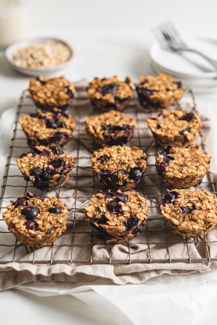 12 blueberry oatmeal cups sitting on a baking cooling rack.