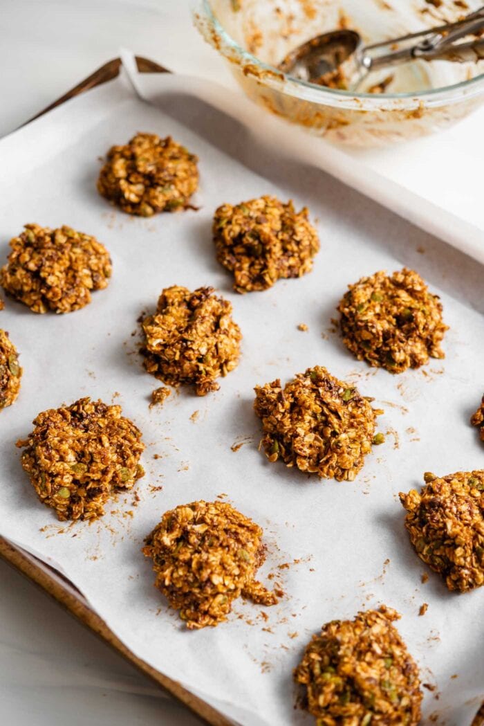 Raw cookies scooped onto a parchment baked-lined baking tray.