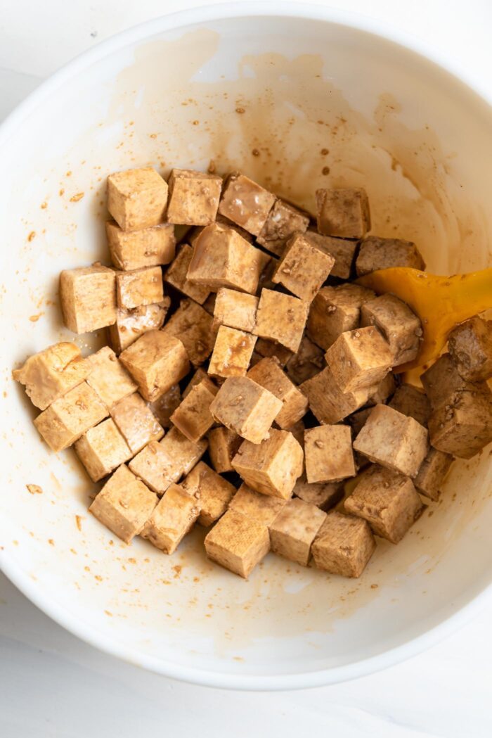 Cubed tofu coated in soy sauce in a bowl.