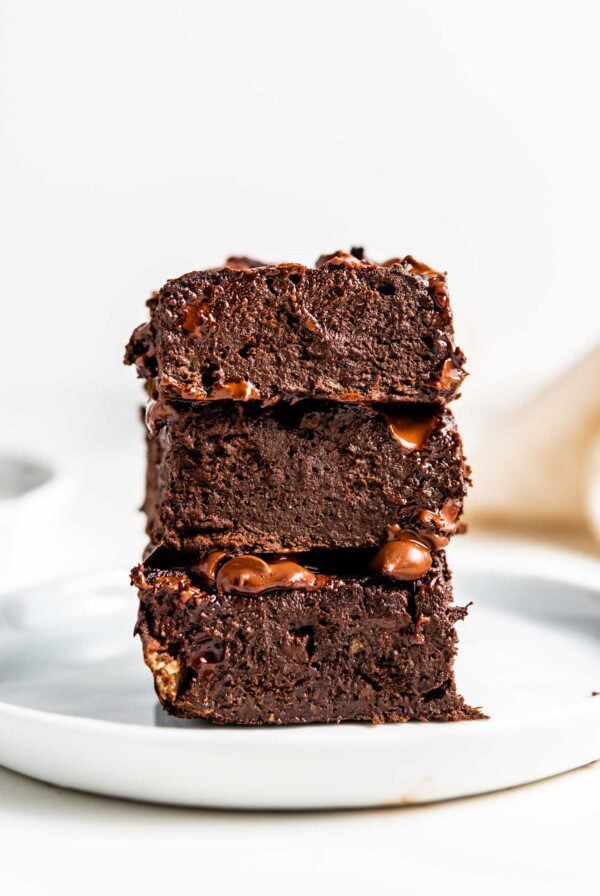 Stack of 3 chocolate brownies on a small white plate.