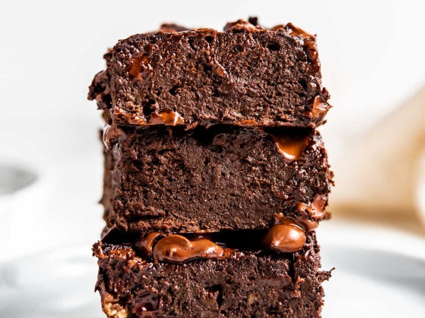 Stack of 3 chocolate brownies on a small white plate.