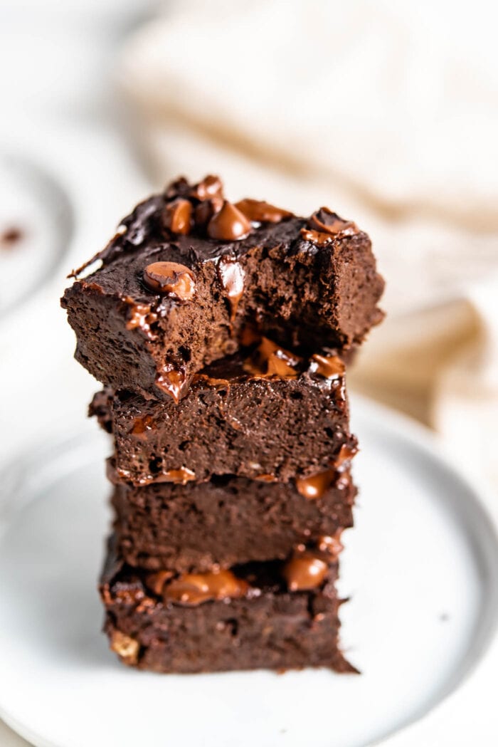 Stack of 4 chocolate brownies with one on top with a bite out of it.