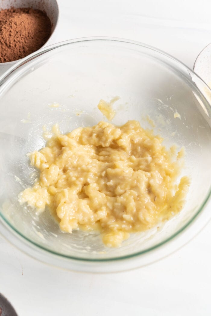 Mashed banana in a glass mixing bowl.