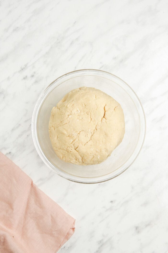 A ball of bread dough in a glass mixing bowl.