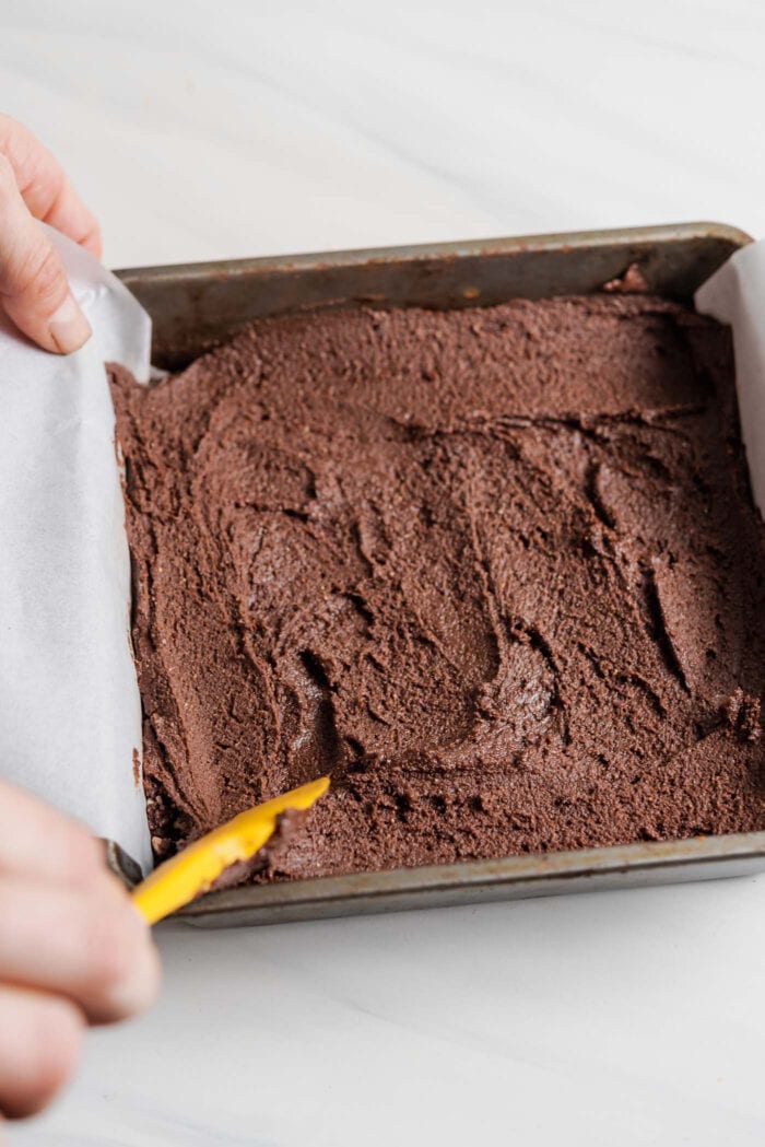 Layer of chocolate fudge spread into a small square baking pan lined with parchment paper.