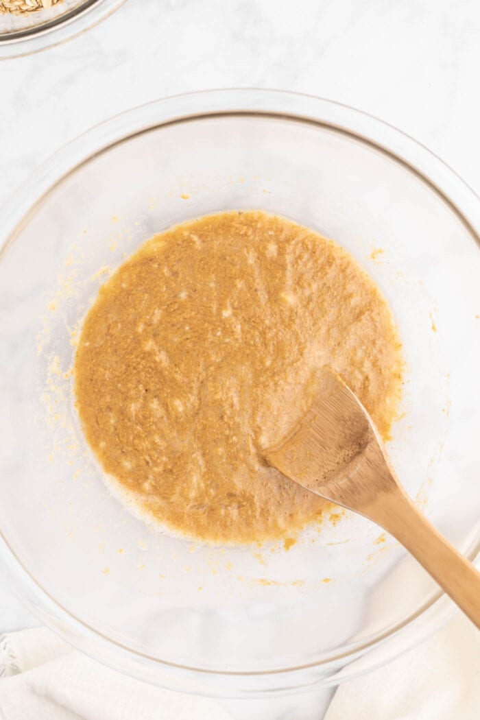 A smooth, creamy batter in a glass mixing bowl with a wooden spoon.