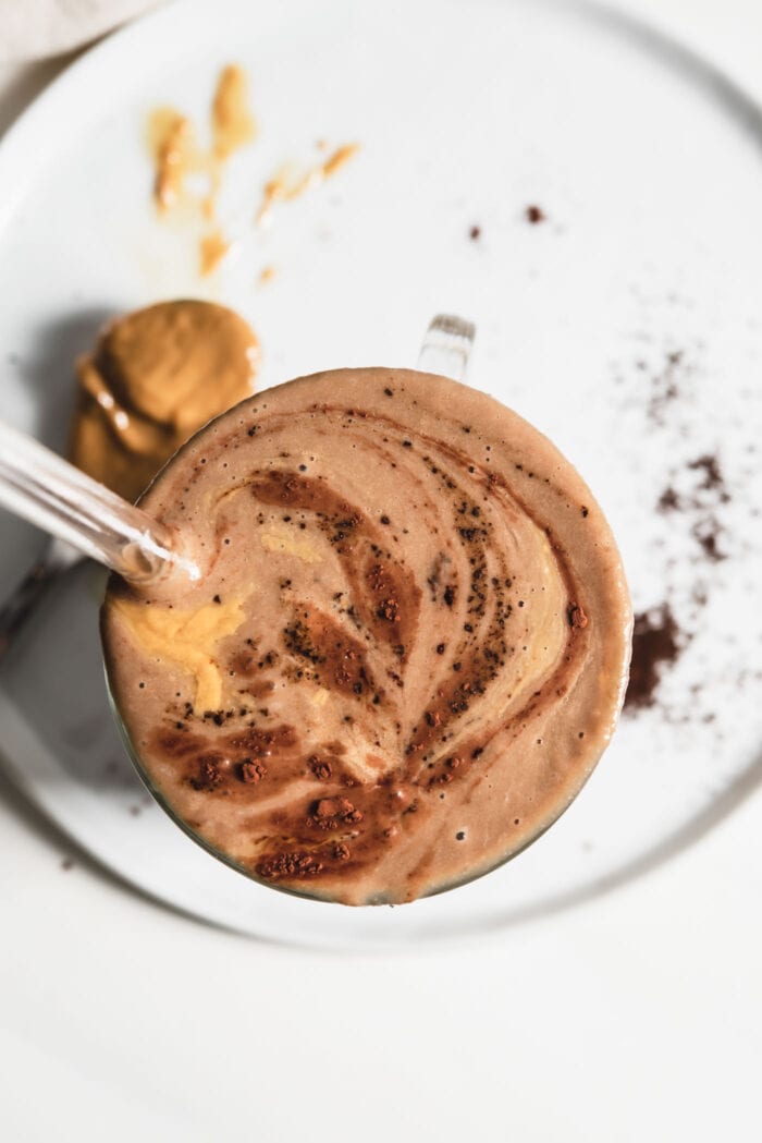 Overhead view of a chocolate smoothie sprinkled with cinnamon in a glass.