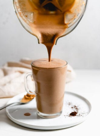 Blender pouring a chocolate smoothie into a glass mug.