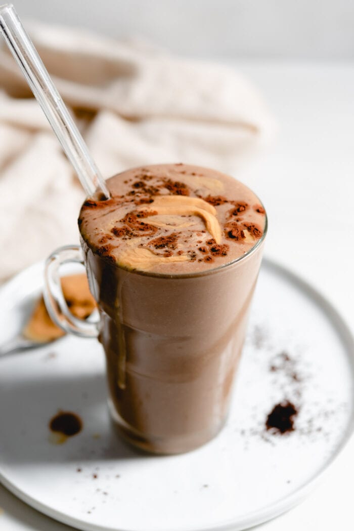 Creamy chocolate smoothie in a glass mug with a straw.