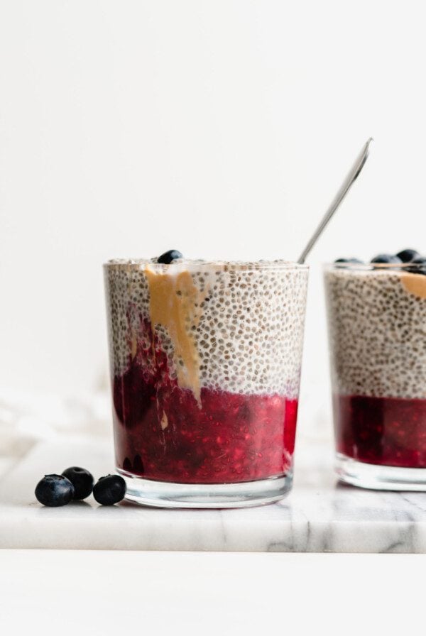 Two jars of peanut butter chia pudding with a layer of jam on the bottom of the jars.