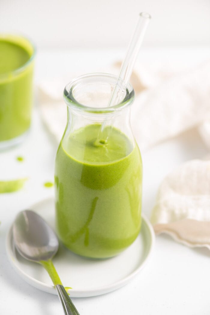 Green smoothie in a jar with another smoothie in the background.