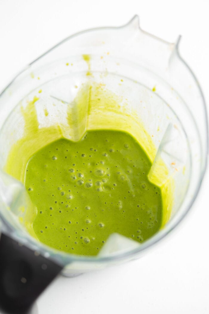 Bright green smoothie in a blender container.