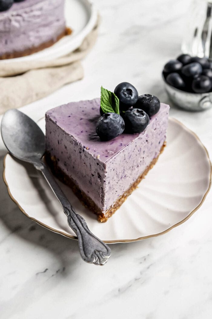 Slice of blueberry cheesecake on a small plate with a spoon.