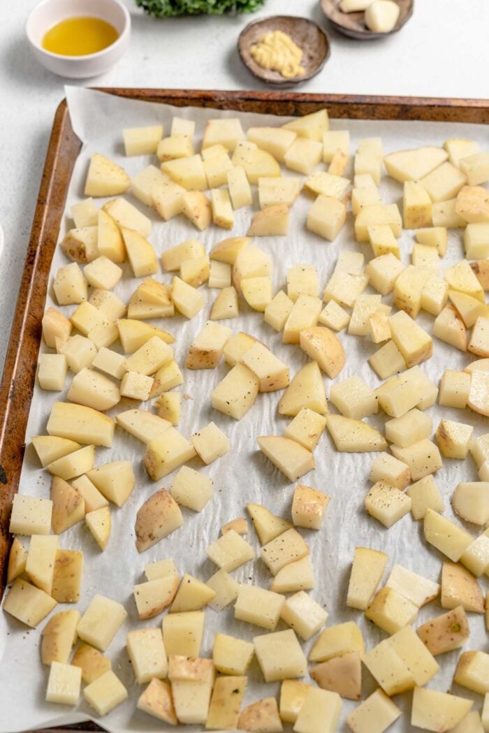 Cubed potatoes on a baking tray lined with parchment paper.