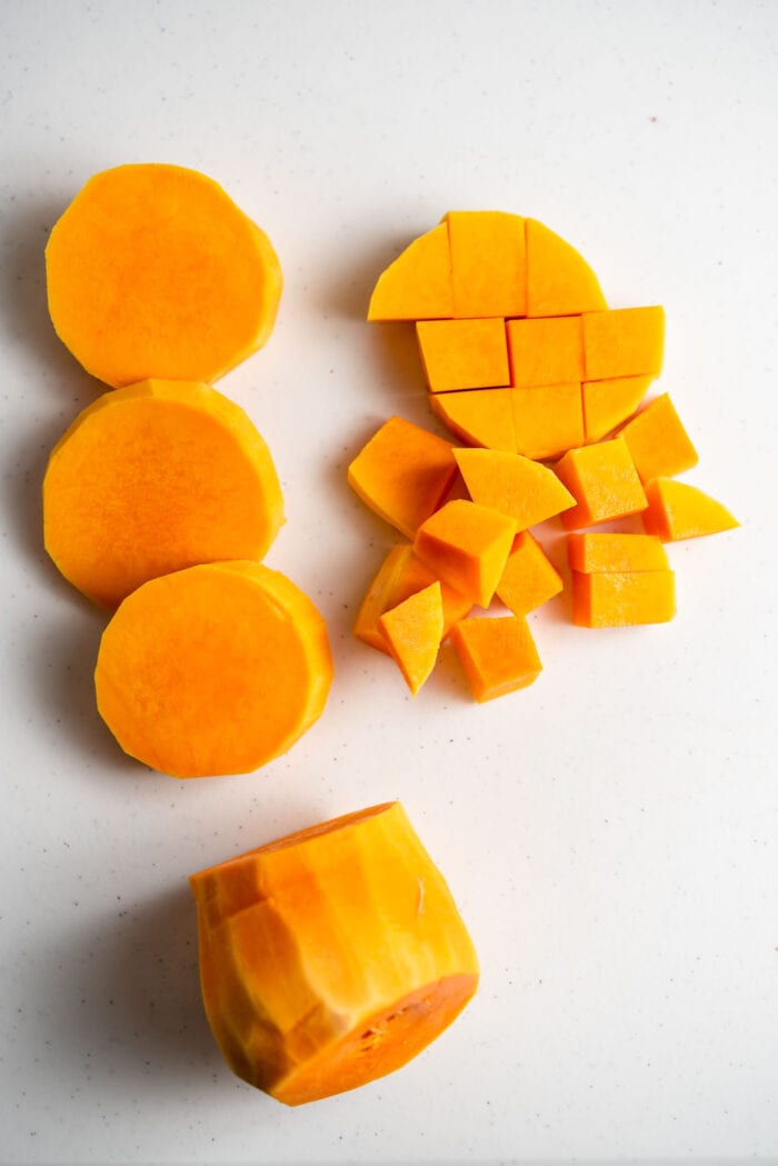 A peeled butternut squash cut into chunks and cubes.