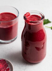 Beet smoothie in a jar with another small glass behind it and a small dish of chopped beets beside it.