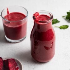 Beet smoothie in a jar with another small glass behind it and a small dish of chopped beets beside it.