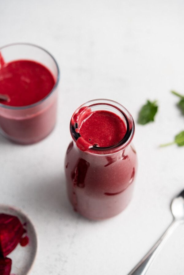 Beet smoothie in a jar with another small glass behind it and a small dish of chopped beets beside it.