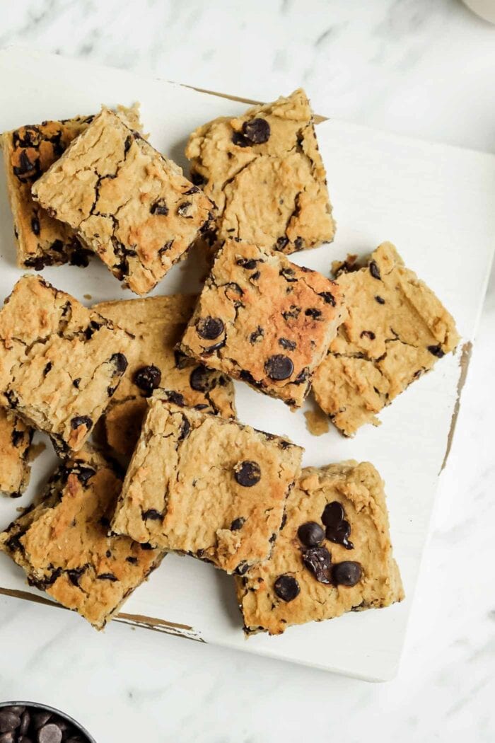 Numerous sliced chocolate chip blondies on a wooden cutting board.