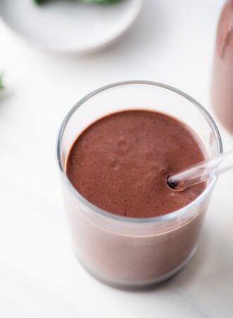 Creamy chocolate cherry smoothie in a glass with a glass straw.