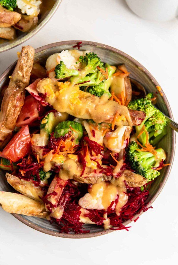 Overhead view of a colourful bowl of vegetables topped with a creamy sauce.