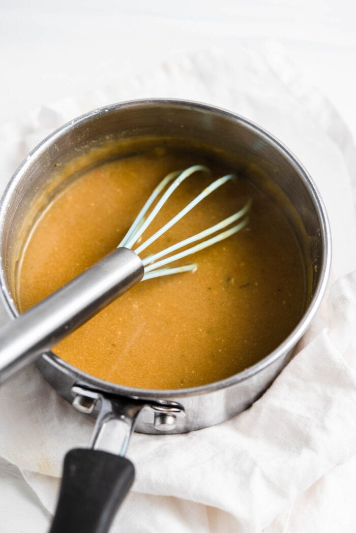Thick miso gravy in a small saucepan with a whisk.