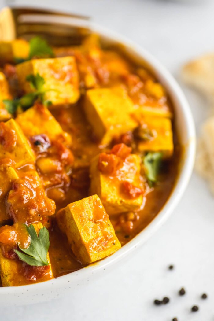 Close up of tofu in a creamy tikka masala sauce in a bowl.