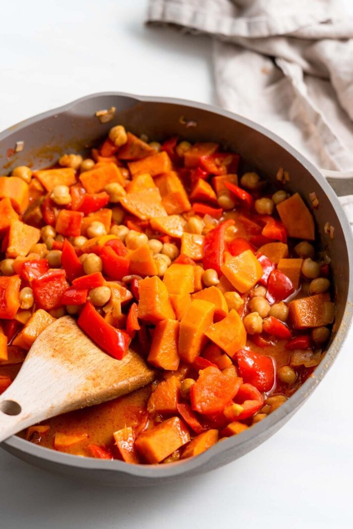 Sweet potato and chickpea curry cooking in a skillet.