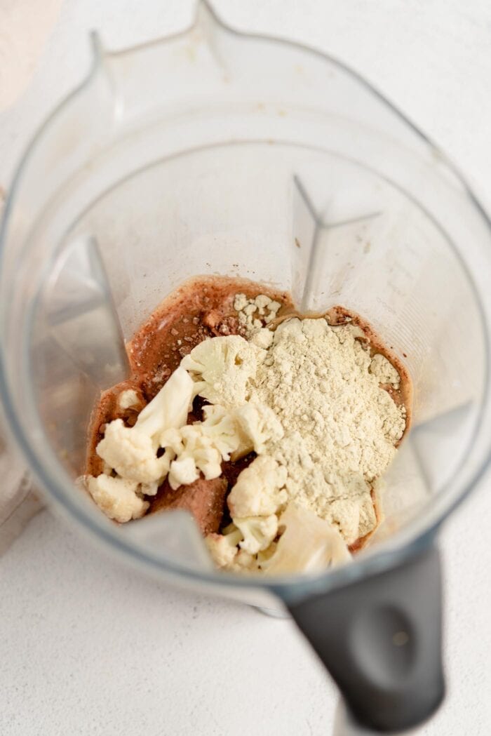 Cauliflower, protein powder and coffee in a smoothie container.