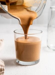 Blender pouring a creamy chocolate smoothie into a glass.