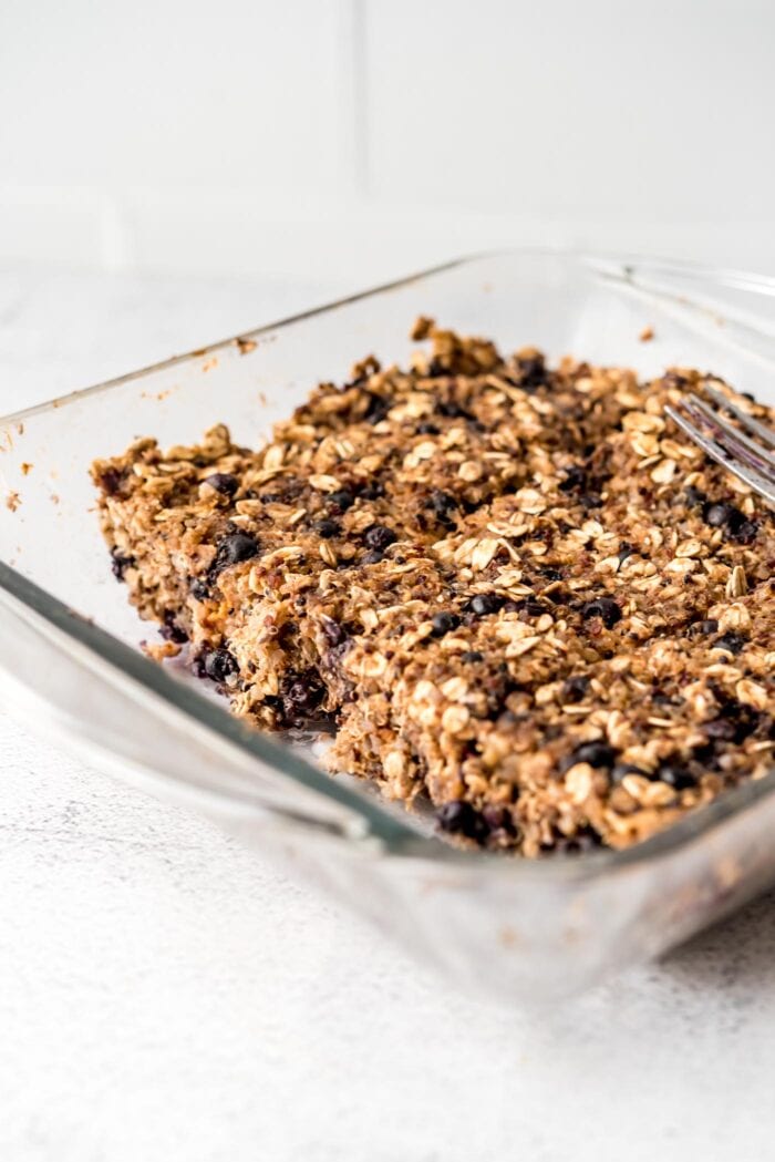 Sliced blueberry baked oatmeal quinoa bars in a glass baking dish.