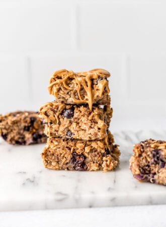 Stack of 3 baked blueberry quinoa oatmeal bars drizzled with peanut butter.