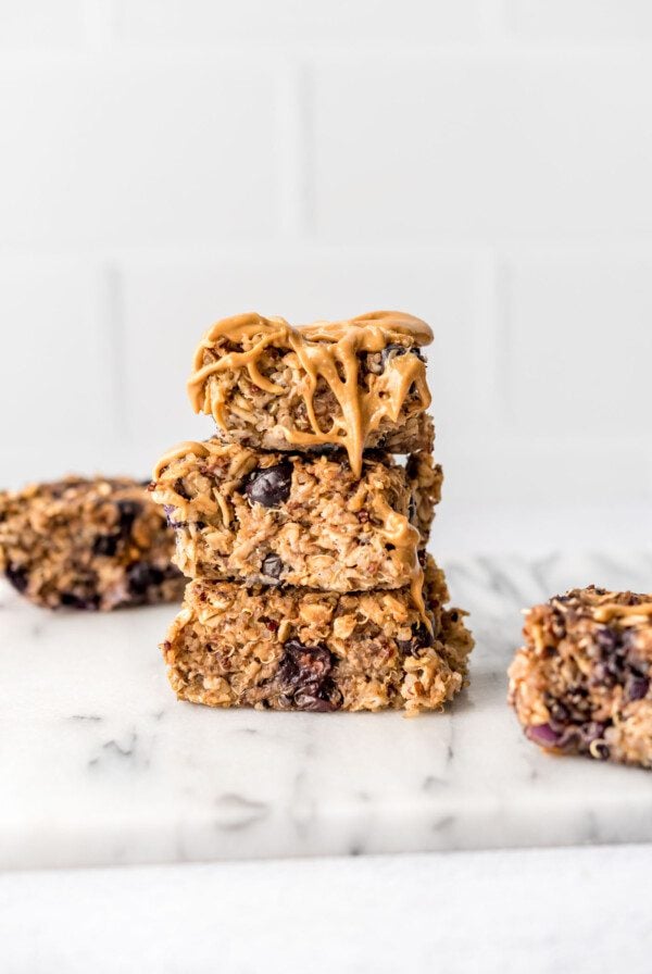 Stack of 3 baked blueberry quinoa oatmeal bars drizzled with peanut butter.