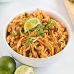 Vegetarian pad thai in a bowl topped with cilantro and a slice of lime.