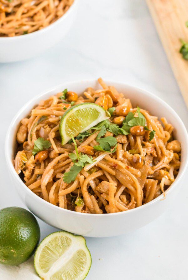 Vegetarian pad thai in a bowl topped with cilantro and a slice of lime.