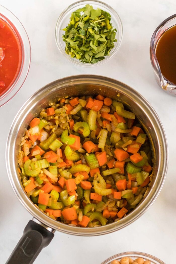 A mixed of cooked diced celery, carrot and onion in a soup pot.