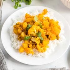 Plate of aloo gobi or curried potato and cauliflower served over a bed of jasmine rice.