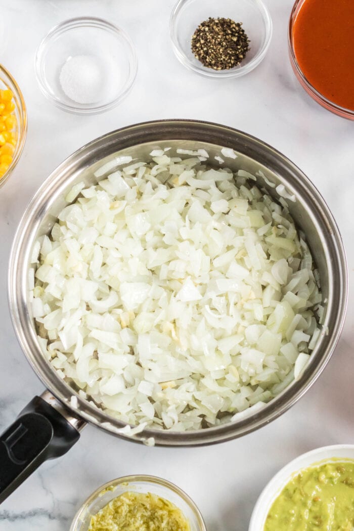 Chopped onions cooking in a large frying pan.