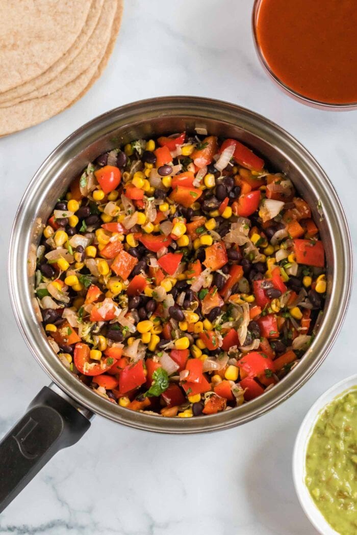 Corn, bell peppers and black beans cooking in a large skillet.