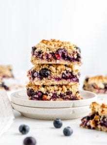 Stack of 3 blueberry crumble bars on a small plate.