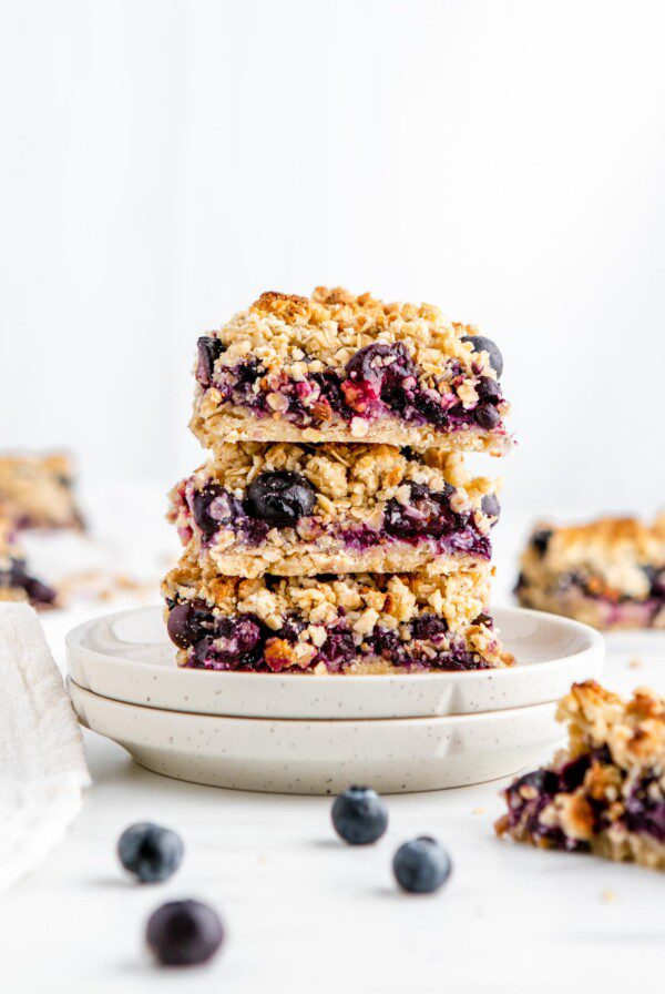 Stack of 3 blueberry crumble bars on a small plate.