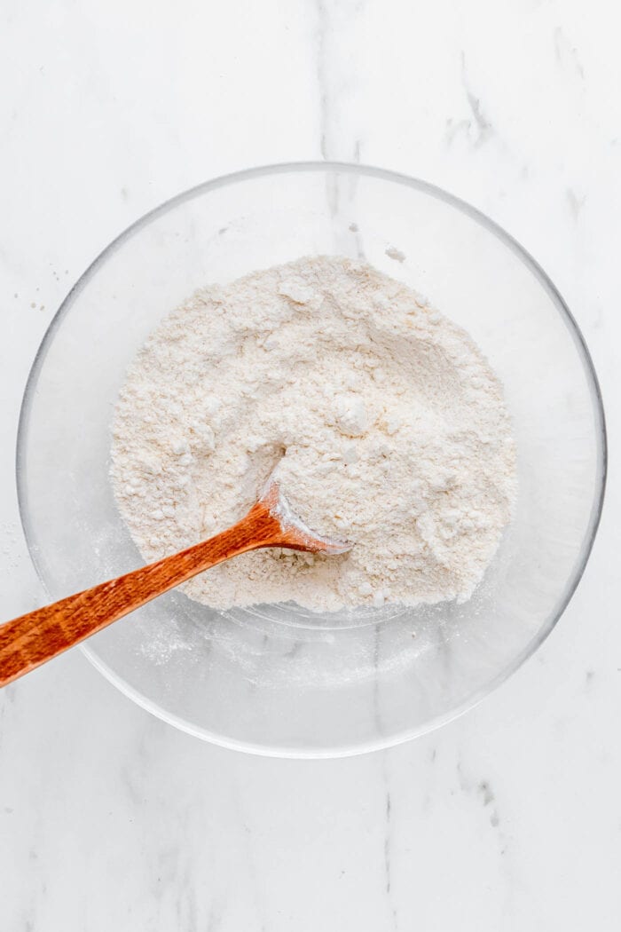 Oat flour and almond flour mixed together in a mixing bowl with a spoon in it.