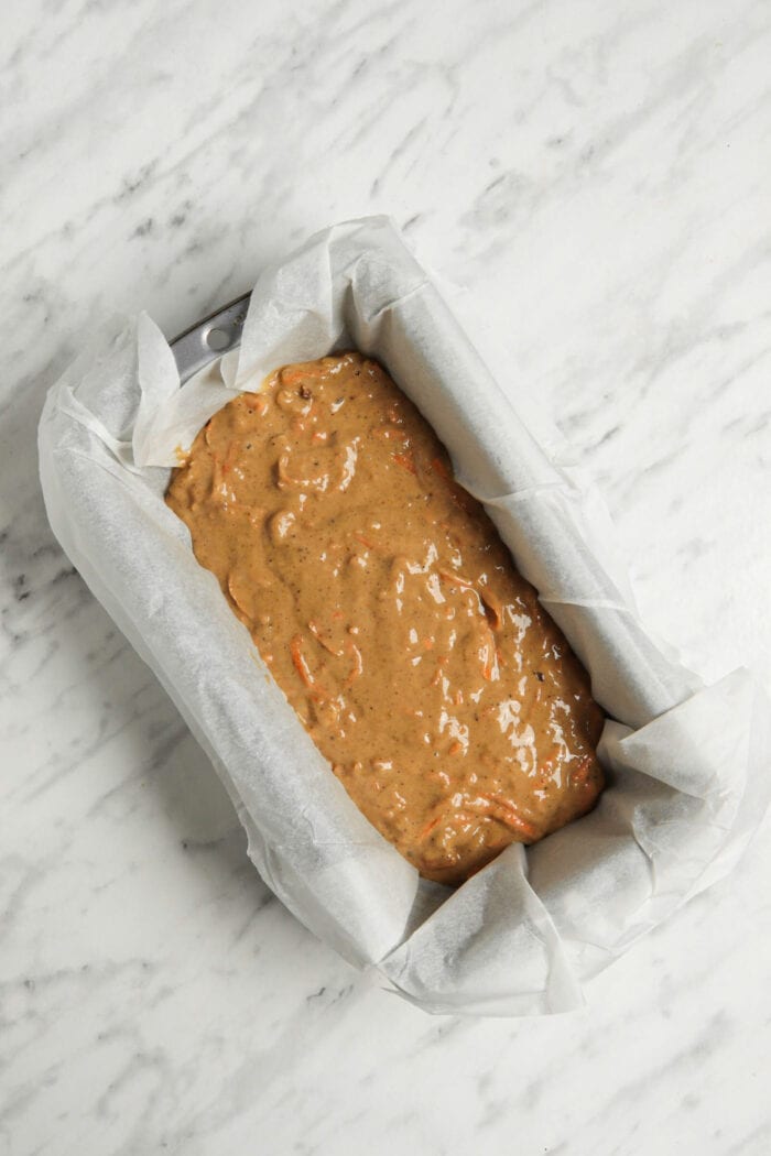 Raw banana bread batter in a parchment paper-lined loaf pan.
